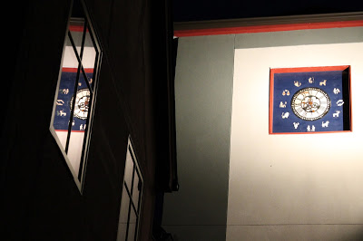 tower clock at night with reflection image in a window