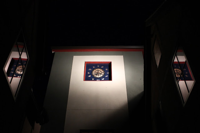 tower clock at night with 2 reflections in 2 windows