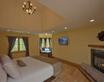 Beautiful room with light yellow walls and king size bed with cream sheets and walnut bed frame and headboard.