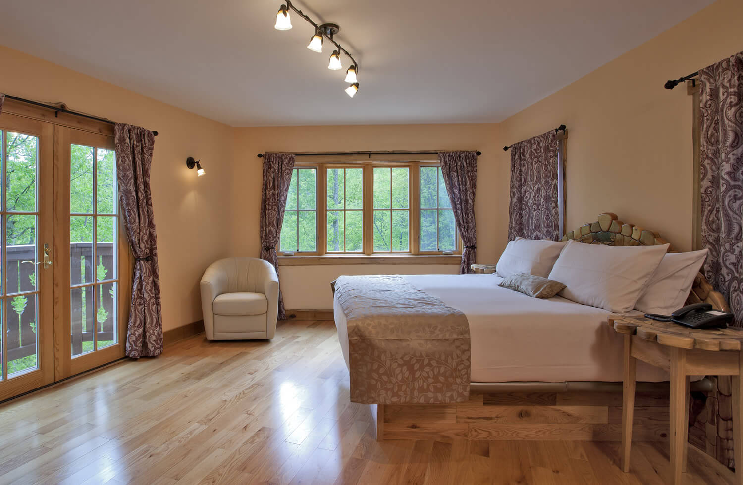 Cozy room with light yellow walls and glass patio doors. One white bed  with many soft pillows.